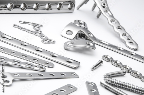 Surgical stainless bone plates and screws on white background in close up view