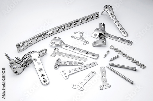 Surgical stainless bone plates and screws on white background