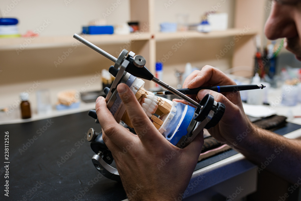 © Aleksandr Kolesnikov - Dental technician working with articulator in dental laboratory