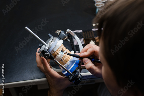 Dental technician working with articulator in dental laboratory