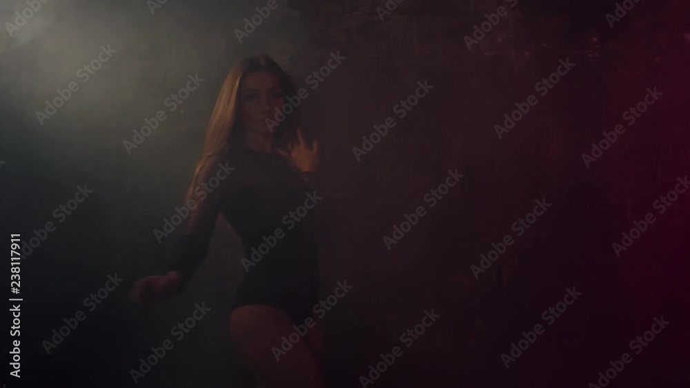 Charming girl is dancing sensually in darkness in dance floor. She is whirling, leaning on wall and lowering in smoke. Shoot with RED RAVEN camera. Charming girl is dancing sensually in darkness in dance floor. She is whirling, leaning on wall and lowering in smoke. Shoot with RED RAVEN camera.