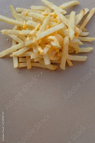 Unhealthy junk food, group of cheesy french fries on brown paper with blank space, fast food concept