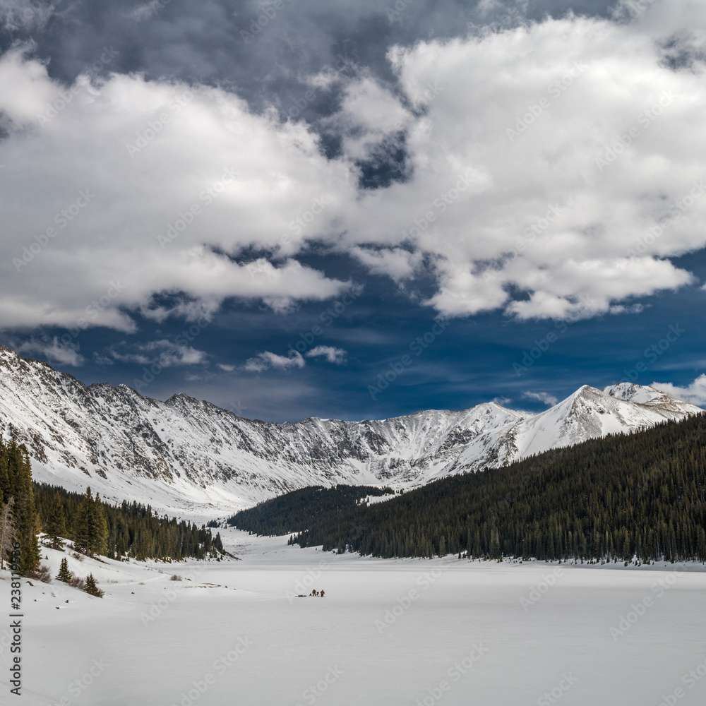 Frozen lake with ice fishermen surrounded by mountains Frozen lake with ice fishermen surrounded by mountains