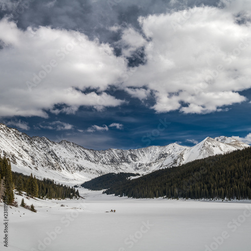 Frozen lake with ice fishermen surrounded by mountains