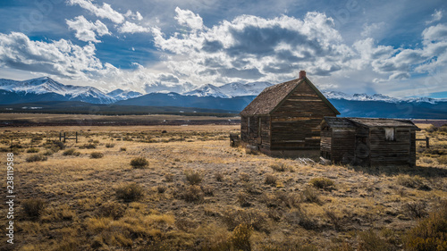 Abandoned cabin on plain with snow capped mountains