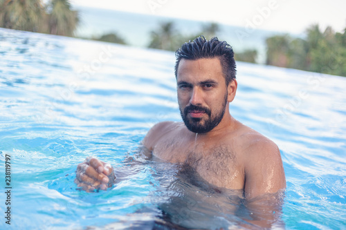 Young attractive sexy Hispanic male, mixed race with beard in the pool, leisure and travel in warm countries