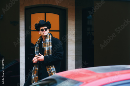 portrait of a stylish man on the street . man in black coat, plaid scarf and hat
