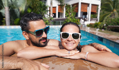 Young attractive couple having fun in the outdoor pool, luxury luxury vacation, real estate in the tropics, honeymoon