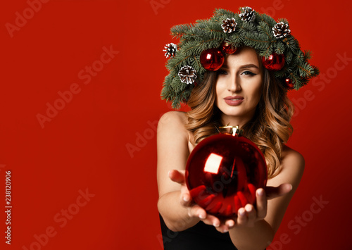 Beautiful woman with Christmas spruce fir wreath with cones and new year decoration balls on red 