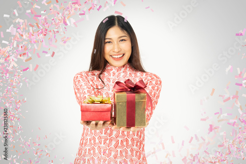 Photo of asian curious woman in red dress rejoicing her birthday or new year gift box. Young woman holding gift box with red bow being excited and surprised holiday present isolated white background