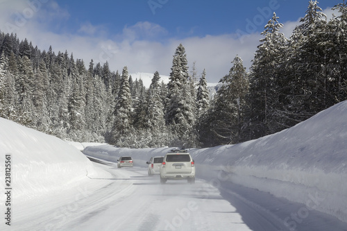 Winter road with cars in snowy forest.