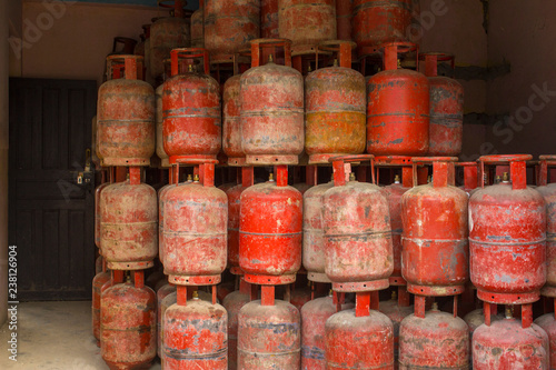 a warehouse of old red gas cylinders standing on top of each other. poor state of gas equipment