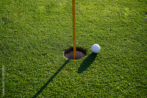 Golf ball on the edge of hole on the green grass