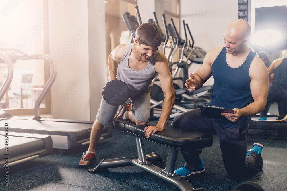 Obraz premium The trainer helps the man doing the exercise.