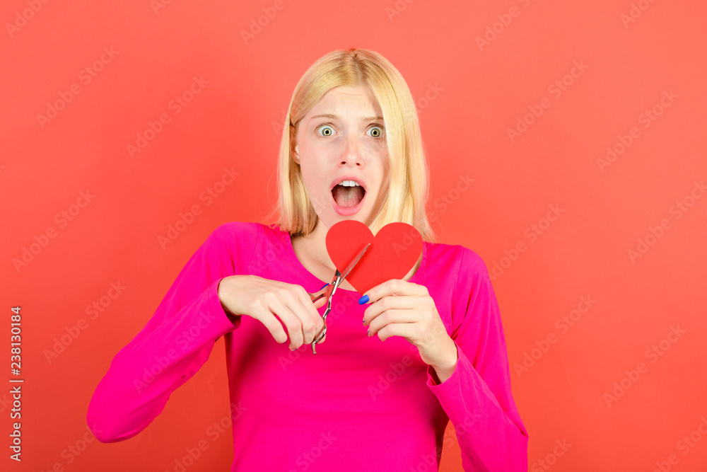 Scared woman cuts with scissors red paper heart to parts. Divorce, parting, separation, end of love. Blonde girl with scissors cutting heart. Female cuts red Valentines heart. Valentine's day concept. Scared woman cuts with scissors red paper heart to parts. Divorce, parting, separation, end of love. Blonde girl with scissors cutting heart. Female cuts red Valentines heart. Valentine's day concept.
