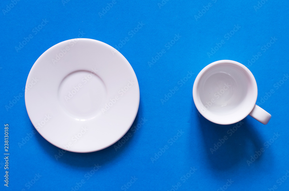 White cup and white plate on the blue background. White cup and white plate on the blue background.