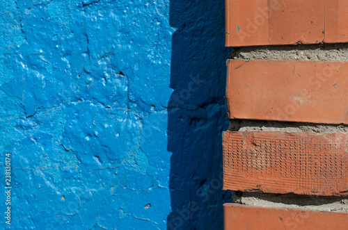 Blue concrete wall and orange brickwall textured background. © Natali