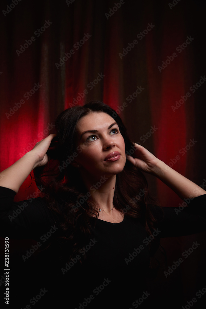 Mysterious portrait of a girl in a black dress in dark room and red light background Mysterious portrait of a girl in a black dress in dark room and red light background