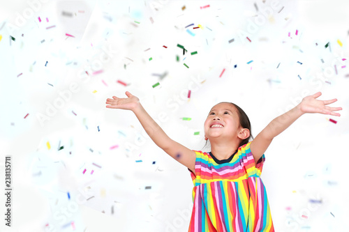 Happy little child girl with colorful confetti on white background. Happy New Year or Congratulation Concept.