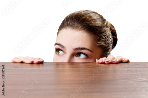 Woman peeping under the edge of wooden table.
