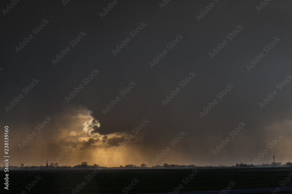 Imposing storm clouds gathering over the Northern Parts of Friesland, the Netherlads, during sunset Imposing storm clouds gathering over the Northern Parts of Friesland, the Netherlads, during sunset