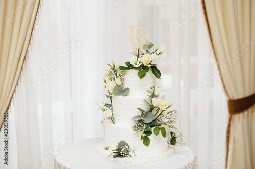  White wedding cake with flowers. The word Love with heart.