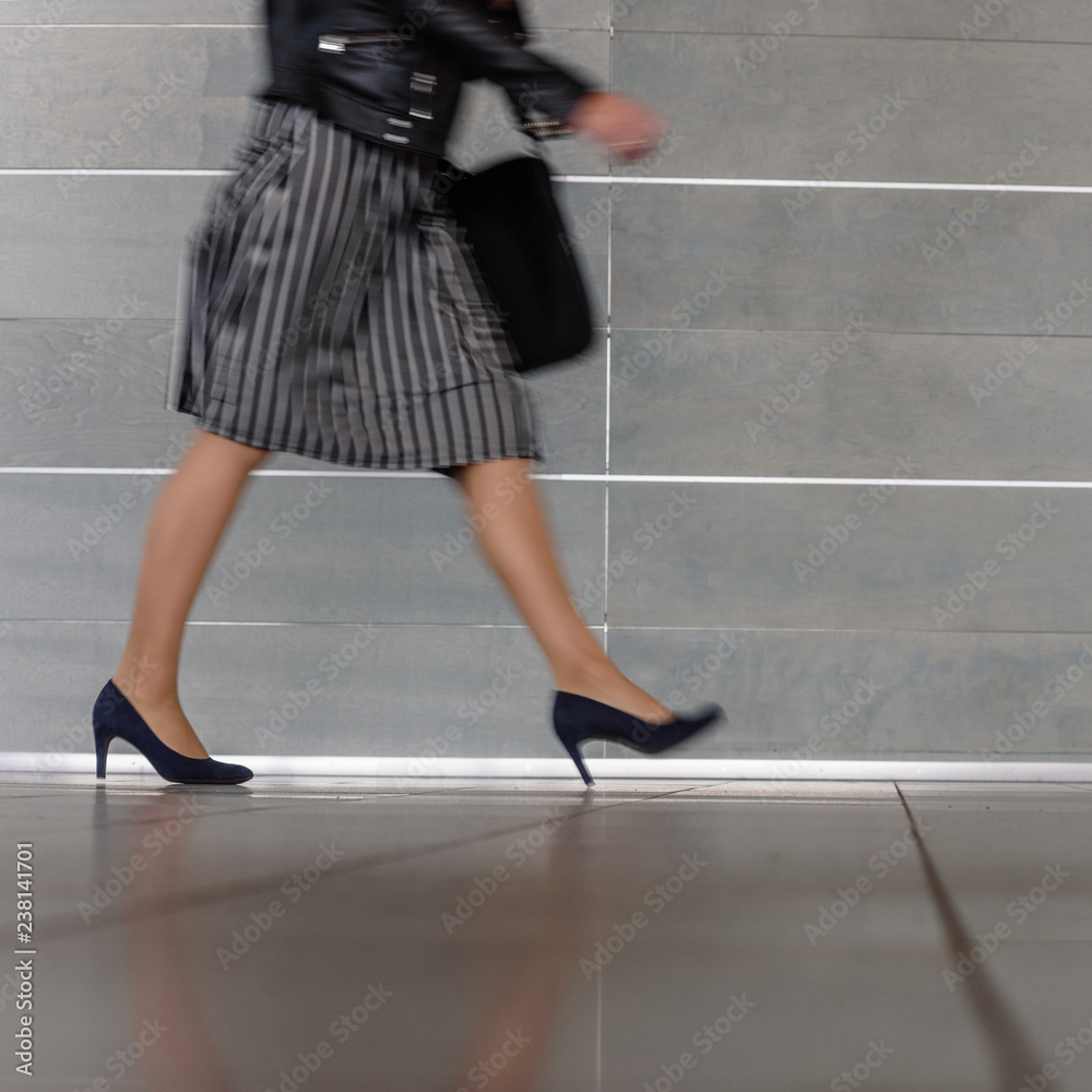 Closeup of elegant busy woman walking on gray background Closeup of elegant busy woman walking on gray background