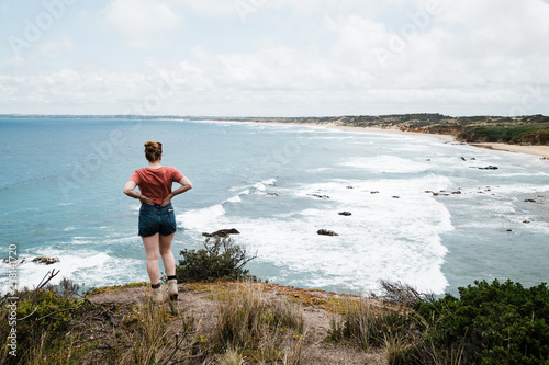 A woman walks along an ocean clifftop