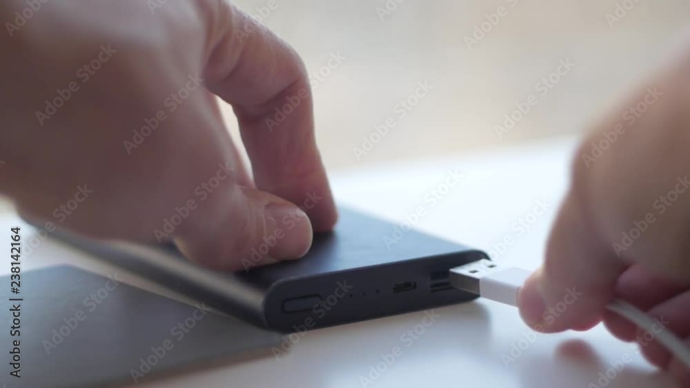 the man pulls out and inserts the cable into the portable charging the man pulls out and inserts the cable into the portable charging
