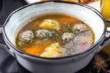 Soup with meat meatballs, potatoes and vegetables. in a white plate on a black background