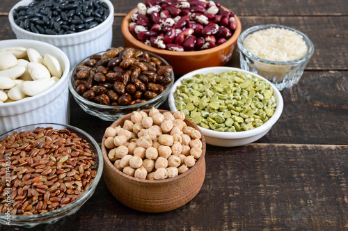 Healthy food dieting nutrition concept, vegan protein and carbohydrate source. Assortment of colorful raw legumes in bowls on a wooden table.