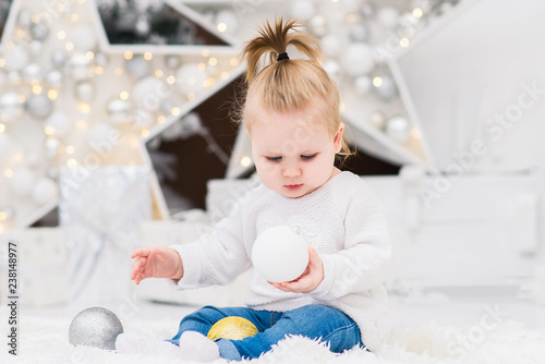 Baby girl on a background of Christmas trees with lights and gift boxes