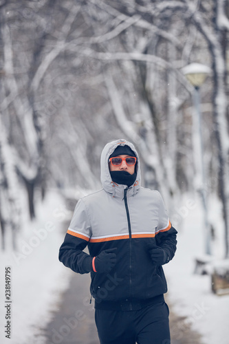 Man jogging in a cold winter snowy day outdoors.