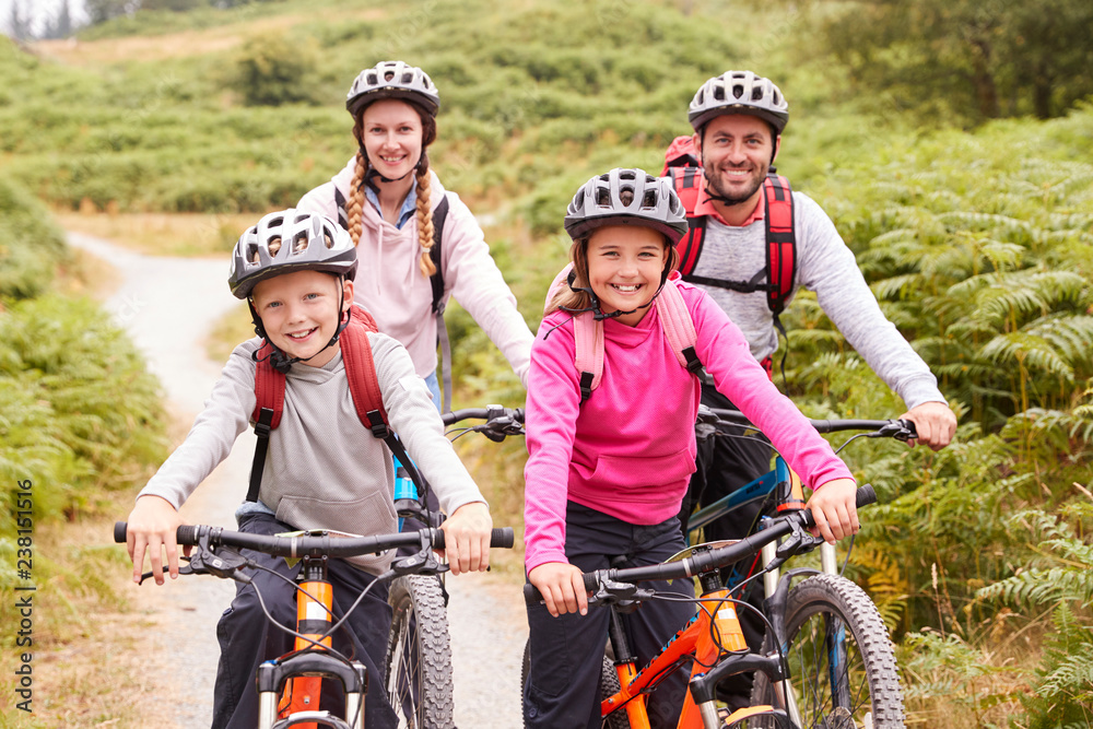 Portrait of parents and children sitting on mountain bikes in a country lane during a family camping trip, front view