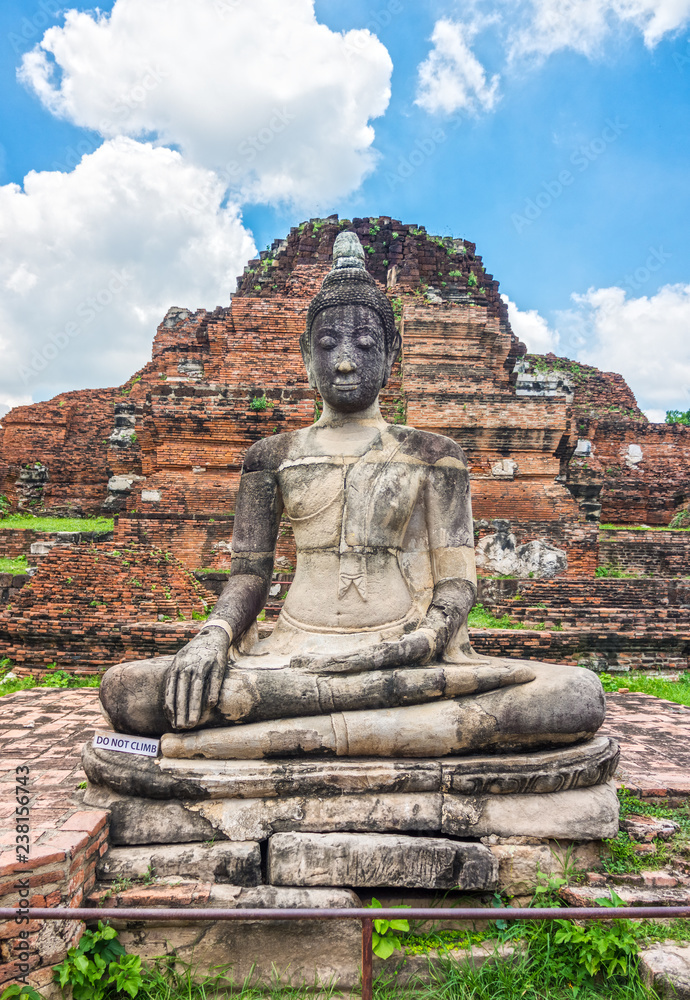 Ancient statues of sitting Buddha image in front of remains of main Phra Pang at Wat Mahathat. The old Buddhism ruins in Ayutthaya, Thailand, Southeast Asia.