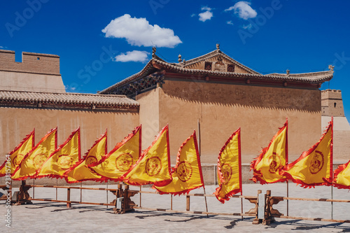 Red and yellow flags in front of traditional Chinese buildings at Jiayu Pass, in Jiayuguan, China