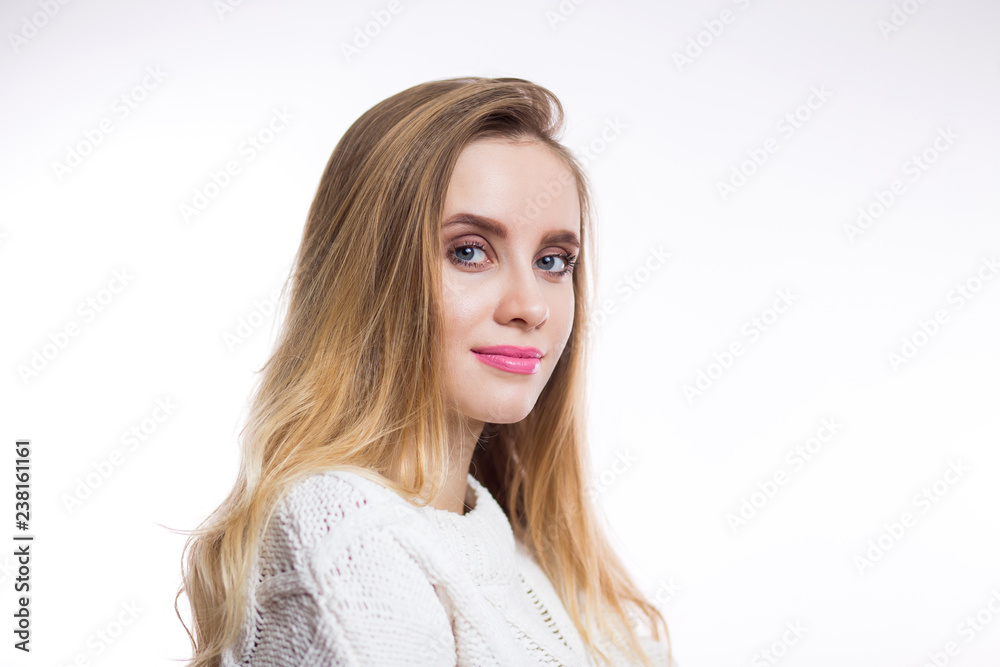 Horizontal closeup portrait of young blonde woman in beige knitted sweater on white background with copy space. Beautiful girl Horizontal closeup portrait of young blonde woman in beige knitted sweater on white background with copy space. Beautiful girl