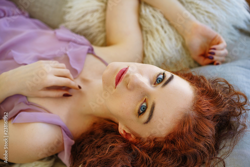 beautiful young woman with red hair lying on the couch