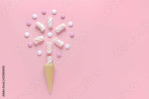 candy, marshmallow and ice cream waffle cone on pink background, concept image