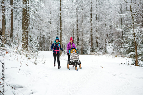 Mother with baby stroller enjoying winter in forest, family time