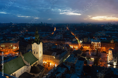 Panoramic night cityscape view on roofs,lights center and domes of Lviv city, Ukraine with a sun flare