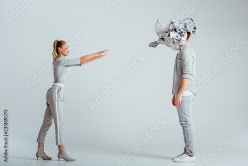 blonde woman throwing pile of clothes at man on grey background