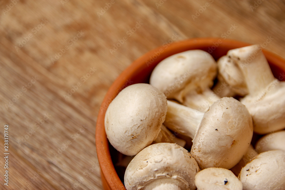 Fresh white champignon mushrooms in brown ceramic bowl on wooden vintage table Fresh white champignon mushrooms in brown ceramic bowl on wooden vintage table