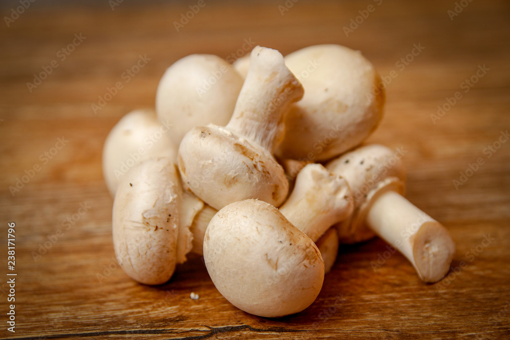 Fresh white champignon mushrooms in brown ceramic bowl on wooden vintage table Fresh white champignon mushrooms in brown ceramic bowl on wooden vintage table
