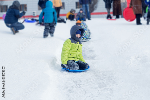 Cute boy rolls down a hill in the snow. Winter sport