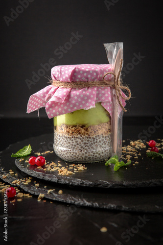 hia pudding or yogurt with granola,  avocado, mango and berries in a jar with a disposable spoon for take away or food delivery.  Healthy breakfast concept and idea. Detox and healthy superfoods. photo