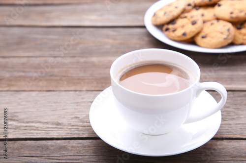 Chocolate cookies on plate and cup of coffee on grey background