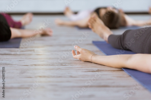 Group of people in yoga class meditating in Shavasana pose. Healthy lifestyle and wellness, recreation concept in fitness studio or gym