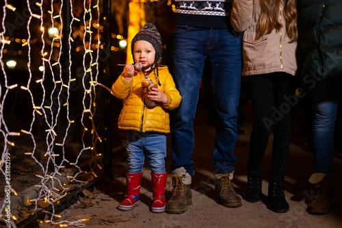 Young boy holding traditional food in frot of family at Christmas market. photo