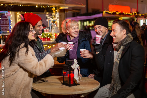 Group of friends laughing and cheering at Christmas market.